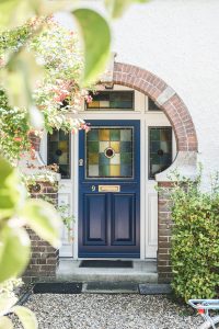 panelled traditional blue timber door, from the anvil aged brass letterbox, ral9010 sidelights, bespoke stained glass unit